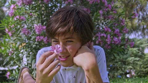 Teenager Boy Lying Prone On Grass Refreshing Smells Flowers Footage.