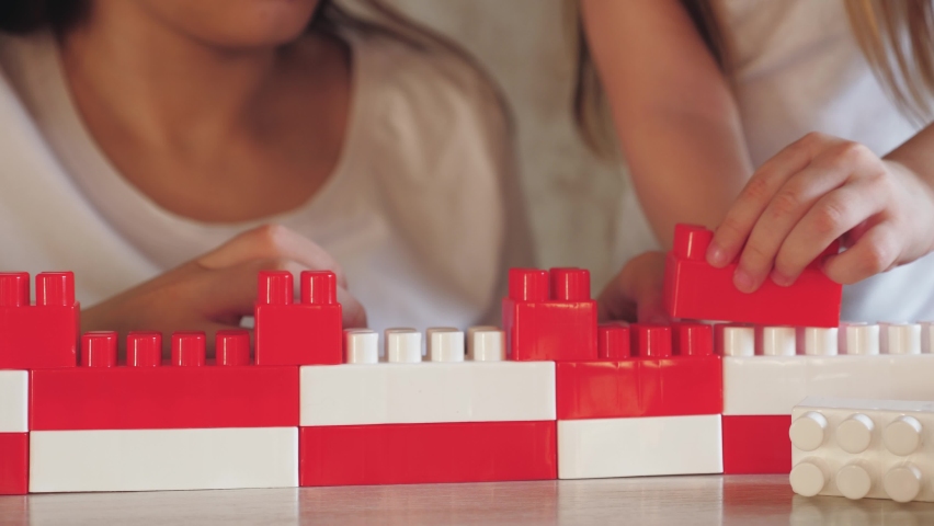 child play constructor with mother. red white colors. parent build together with kid from toy lego brick. teamwork. psychologist deals with child. happy family. group game constructor. chidhood dream