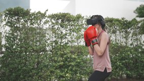 slow motion of young Asian woman, using digital virtual reality goggles and boxer glove to boxing workout, sport video game virtual technology entertainment, reality futuristic exercise training