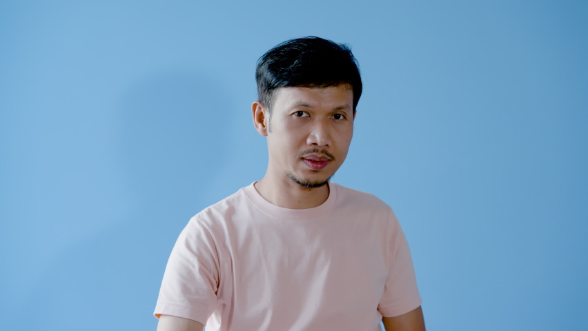 4K, Asian man mustache, Make a face, cover your eyes. put the other hand forbidden from approaching, out of fear, not wanting to look. Body language. Separate indoor studio on a blue background.