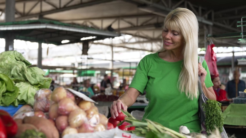 Blonde woman walking threw the market and picking favourite vegetables