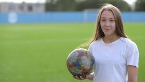 Portrait of a Happy attractive woman with a soccer ball in her hand smiling and looking at the camera on the background of the soccer field. urban lifestyle - Powered by Shutterstock - Get 15% off with code: PIKWIZARD15