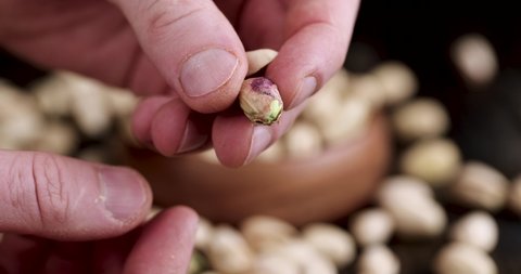 show fried pistachios with cracked shells, delicious crispy pistachios in a man's hand
