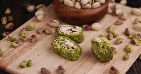 put fresh Turkish delight with crushed pistachios and chocolate on a board, fresh Turkish delight with green pistachios is put on a wooden surface