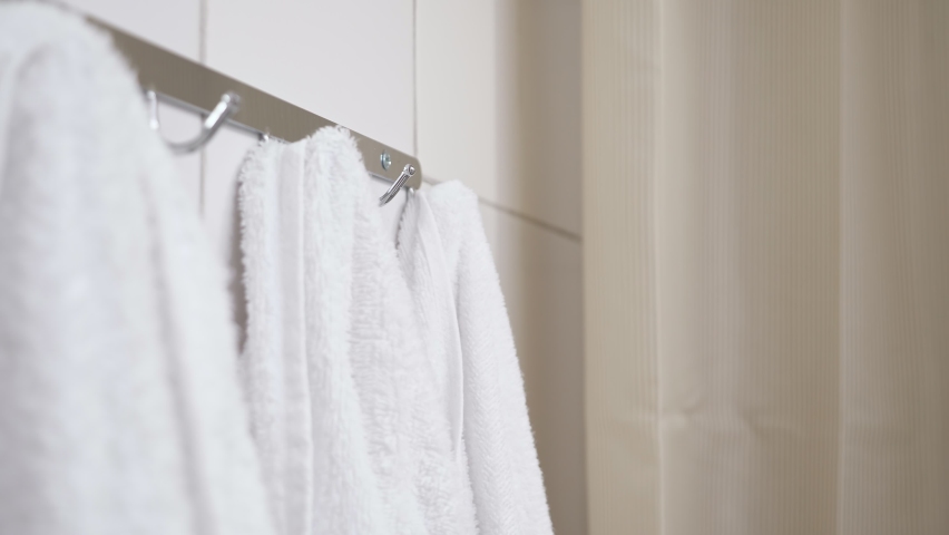Female hand pulls back bath curtain and removes towel from hook. Woman takes terry towel after taking shower during morning routine | Shutterstock HD Video #1091441941