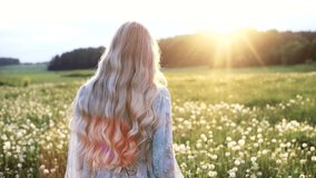 free young woman long-haired blonde walks in a field of dandelions. concept of youth dream, agriculture. happy young woman running through farmland in summer at sunset.