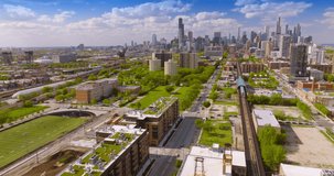 Road and parallel subway railways going through the city. Sunny scenery of green Chicago district at daytime. View from top.
