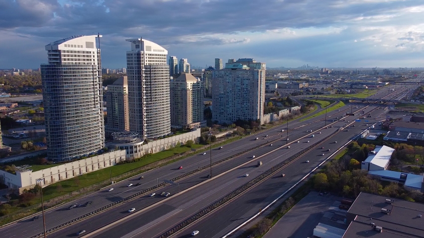 Residential condominium apartment buildings along Highway 401 in Toronto, Ontario with busy traffic and transport trucks; aerial 4K