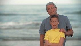 Adolescent grandson with grandfather against the ocean. Family portrait outdoors. Close-knit younger and older generations. Grandpa is a friend and mentor - Powered by Shutterstock - Get 15% off with code: PIKWIZARD15