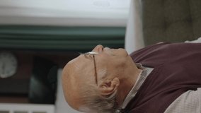Sad old man with glasses is alone at home.The worried old man was lost in thought. Loneliness grief concept. He feels anxious alone at home.Video for the vertical story.