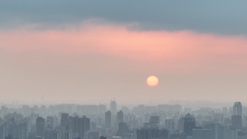 Drone aerial view of City in the dusk and the orange sunset glow. Flying over the city with rows of buildings, beautiful sunset Shanghai China. Business, travel and life style concept b-roll footage.