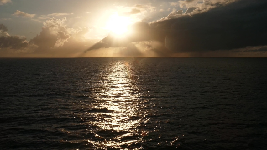 Sun lens flare with sunset over ocean view from moving cruise ship