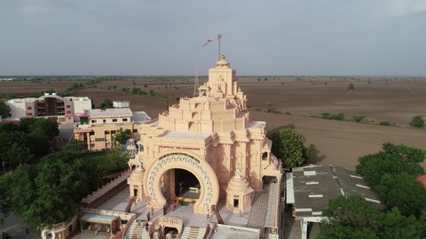 Palitana , Gujarat , India - 06 14 2022: Aerial rotating shot of Palitana temple with empty field in the background. The Palitana temples of Jainism are located on Shatrunjaya hill by the city of Pali
