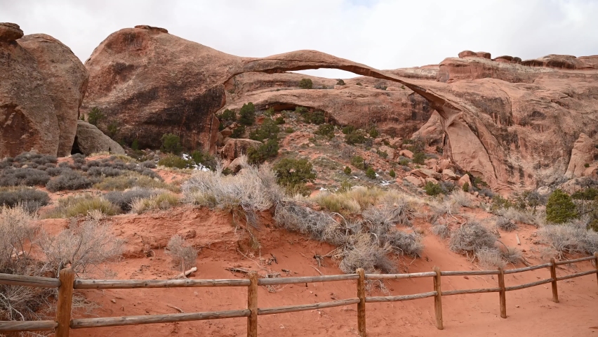 Hikers standing at Landscape Arch overlook in Arches National Park on an overcast day, static