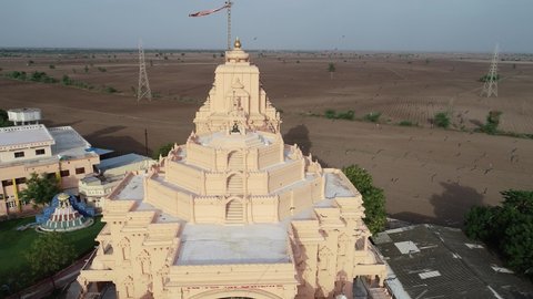 Palitana , Gujarat , India - 06 14 2022: Aerial shot of top of the Palitana temple with empty field in the background in Gujrat ,India. Some of the intricately carved marble shrines making up the temp