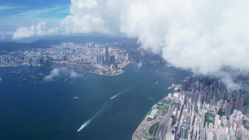 Aerial view flying along the West of Victoria Harbour, Hong Kong, cloudy day