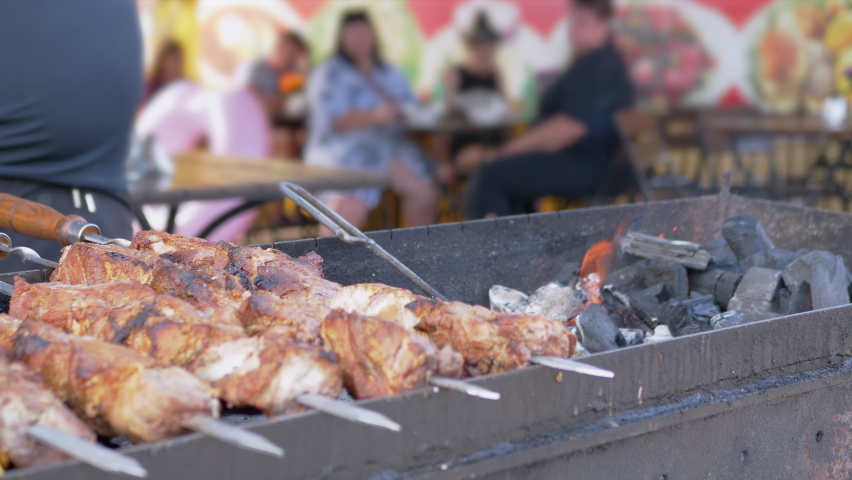 Juicy Appetizing Pork Kebab is Fried in Smoke on the Grill, over an Open Fire. Preparing fried meat on skewers, barbeque on hot coals. Fast food trade, sale eat in a summer cafe, restaurant.