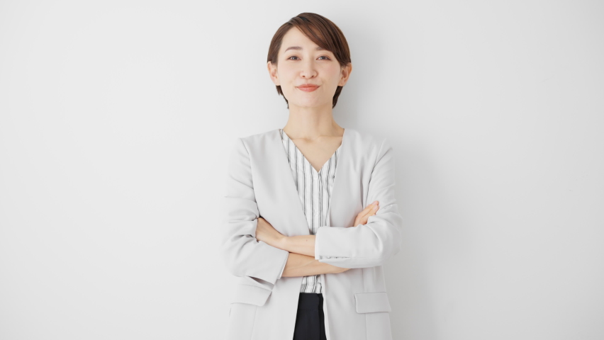 A career woman standing against a white wall.