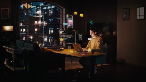Handsome Young Man Sitting at a Desk at Home, Working on Laptop in Living Room. Internet of Things Concept with Animated VFX of Different Social Media Posts and Emojis Popping Out of the Computer.