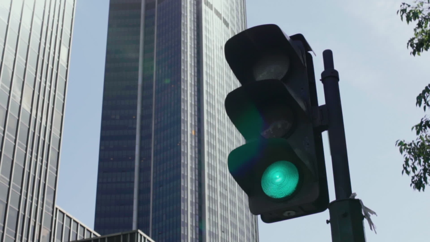 vertical traffic light with blue sky and skyscraper in the background.  Royalty-Free Stock Footage #1091478797