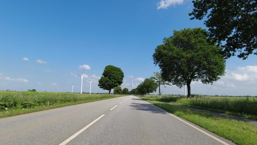 Driving towards wind turbines in the nature. First person view of road towards eco friendly renewable energy turbines | Shutterstock HD Video #1091479259