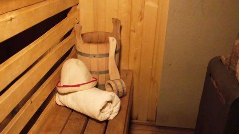 Traditional old Russian bathhouse SPA Concept. Interior details Finnish sauna steam room with traditional sauna accessories set basin towel aroma oil scoop felt. Relax country village bath concept