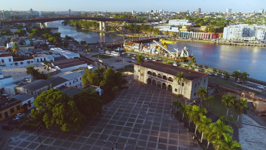 Historical cultural monument in the Dominican Republic, aerial view. City square in the evening rays of the setting sun. City bridge over the river in Santo Domingo. Landscape of the evening city.