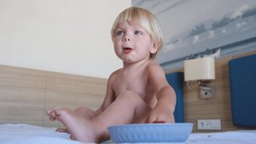 a little boy sits on a bed and eats strawberries - Powered by Shutterstock - Get 15% off with code: PIKWIZARD15