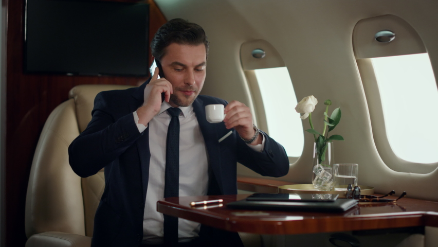 Busy man finishing phone call in luxury jet. Focused manager drinking coffee traveling business class airplane. Handsome businessman ending mobile conversation. Successful finance analyst talking cell - Powered by Shutterstock - Get 15% off with code: PIKWIZARD15