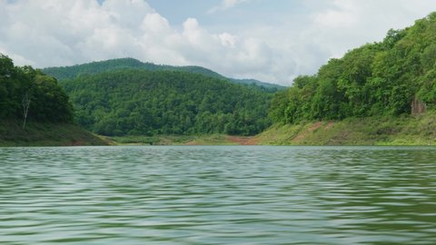 4K Cinematic landscape nature panoramic footage of the Mae Kuang Dam Lake at Doi Saket, Northern Thailand on a sunny day while sailing on a moving boat, close to the water.