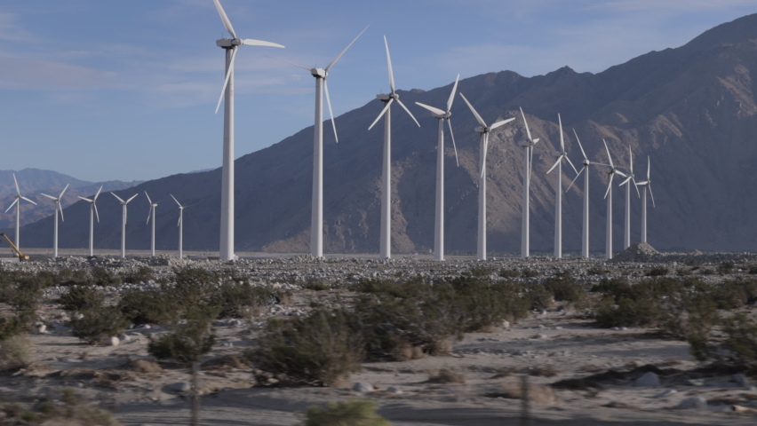 Windmills pass by as seen from the passenger side of a car driving down the highway in California. | Shutterstock HD Video #1091496601