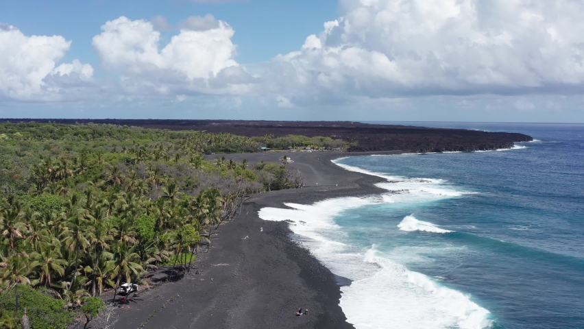 Close-up aerial shot flying over a newly formed black sand beach on the coast of the Big Island of Hawaii. 4K Royalty-Free Stock Footage #1091496635