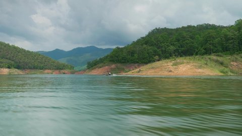 4K Cinematic landscape nature panoramic footage of the Mae Kuang Dam Lake at Doi Saket, Northern Thailand on a sunny day while sailing on a moving boat, close to the water.