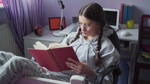 A brunette girl is reading a book. A young girl gets angry while learning.