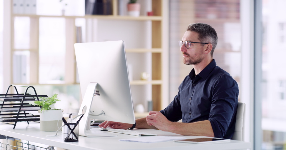 Resolving client complaints via email. 4k video footage of a handsome mature businessman sitting alone in his office and using his computer.