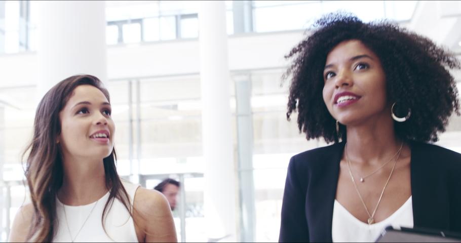 4k video footage of two confident businesswomen walking together with digital tablets on their hands at work