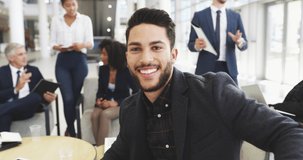 Your smile says a lot about you. 4k video footage of a young businessman smiling in an office with his colleagues in the background.