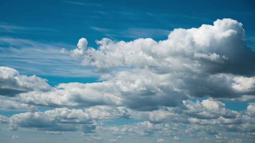 White fluffy clouds slowly float through the blue daytime sky timelapse. Beautiful skies are moving. Airy snow-white clouds move to the side.
