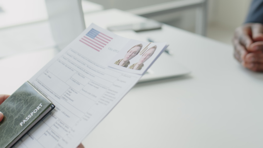 Close up tilt up shot of African American visa officer taking documents and passport form applicant and asking questions during interview in U.S. embassy Royalty-Free Stock Footage #1091509695