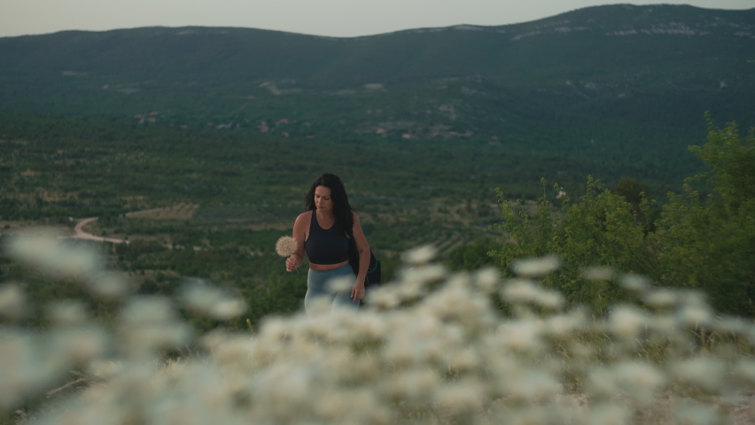 The girl climbs the mountains at sunset. Beautiful woman goes hiking on mountain peaks.
