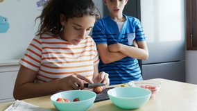 Two siblings cutting fresh strawberries in the kitchen