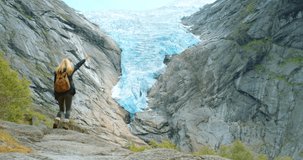 4k video footage of a young woman dancing while exploring the mountains of Briksdal Glacier