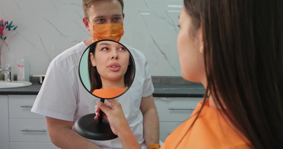 dentistry, young woman looks at her beautiful teeth in mirror after treatment