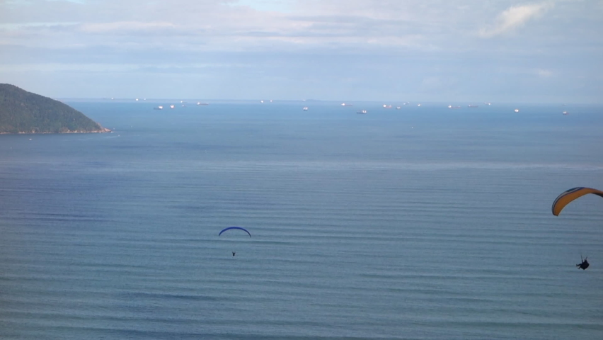 Paragliders drift high above ocean water with ships on blue horizon Royalty-Free Stock Footage #1091517723