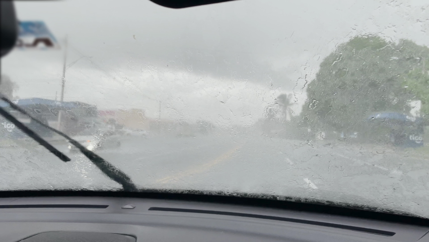 POV: First person view of windshield wipers quickly cleaning the glass during a severe tropical rainstorm. Driving through an exotic storm engulfing Panama as you explore the scenic Latin America. | Shutterstock HD Video #1091520435