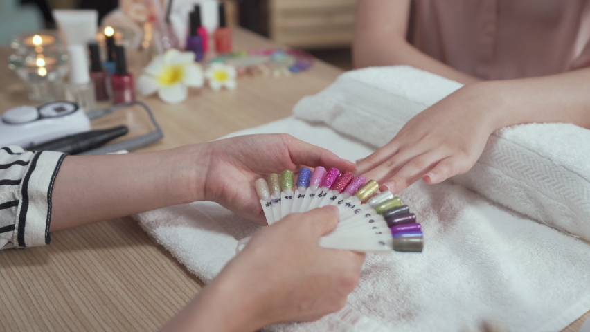 natural fingers touching colorful palette compare. close up female client hands choosing bright summer nail polish in beauty art salon. manicurist showing customer sample in manicure studio Royalty-Free Stock Footage #1091521717