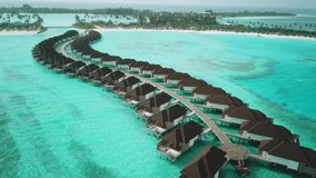 Aerial drone video of exotic turquoise paradise with sandy beach and blue lagoon in tropical Maldives. Aerial view of water villa bungalows. High quality 4k footage. Luxurious resort in Maldives.