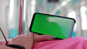 Female hands are holding a smartphone and touching the screen with their fingers. On-screen green rear background.