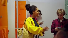 Young high school students meeting and greeting near locker in campus hallway talking and high fiving. - Powered by Shutterstock - Get 15% off with code: PIKWIZARD15