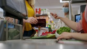 Close-up of woman giving money at the cash desk in supermarket during pandemic. - Powered by Shutterstock - Get 15% off with code: PIKWIZARD15
